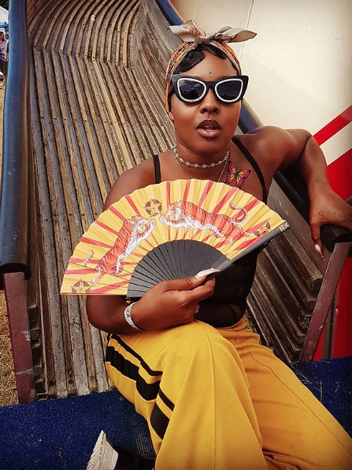 Girl wearing hip hop style clothing holding the Tiger Tiger Hand-Fan at the bottom of a helter-skelter. 