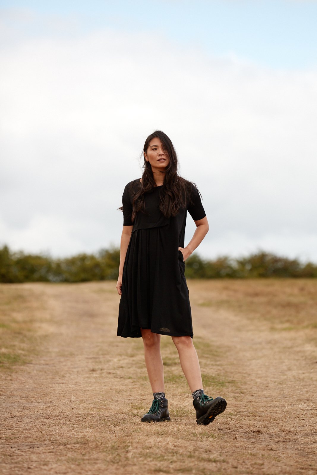 Woman wearing the Asmuss Asymmetric Pleat Dress in Black.  It can take you from the office, to gallery or restaurant 