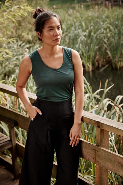 Woman wearing the Asmuss Panelled Tank in Pine Green.  Stylish and sustainable performance womans where for any travel adventure or even everyday