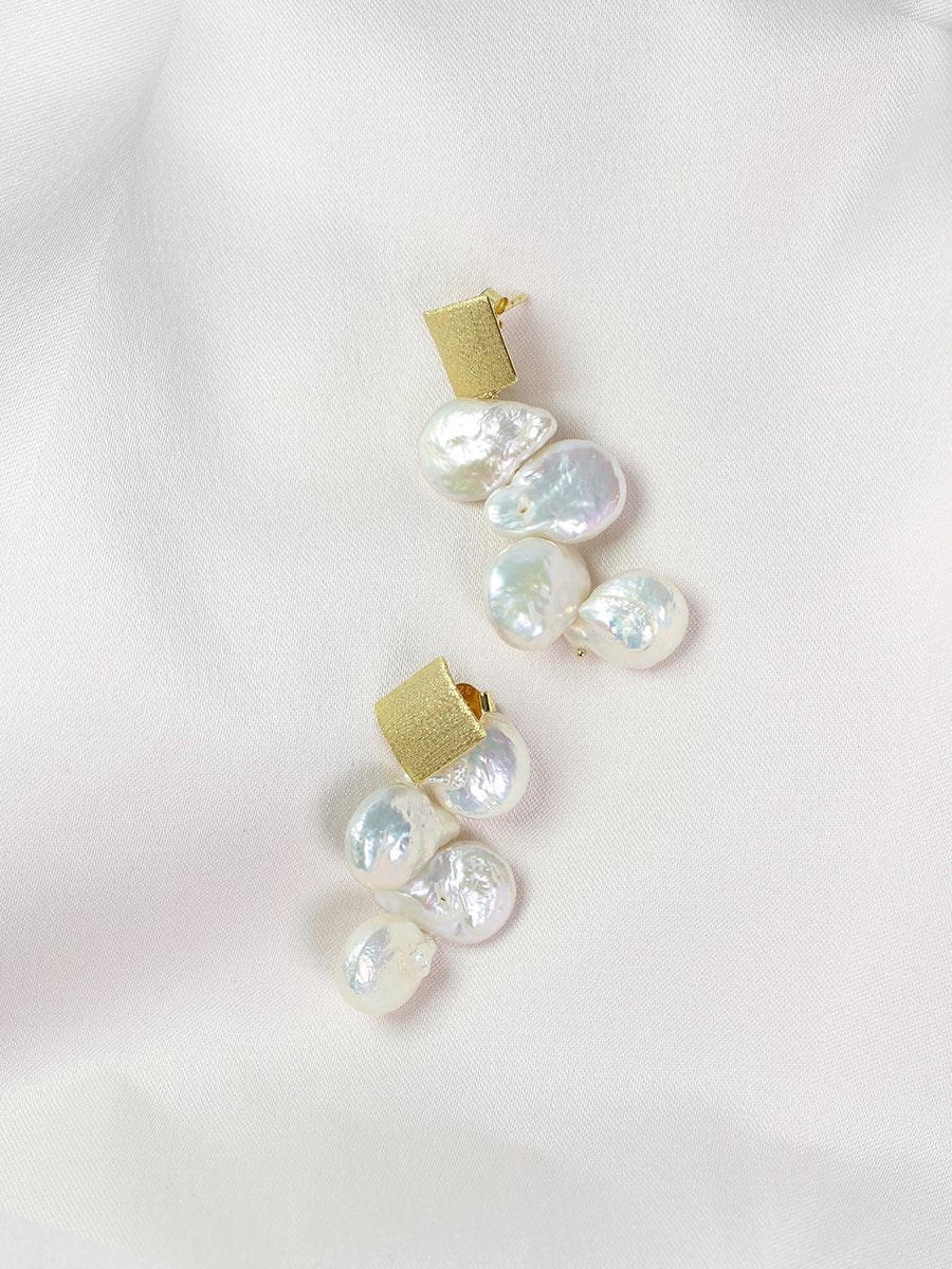 Pearl earrings cascading from a square gold stud