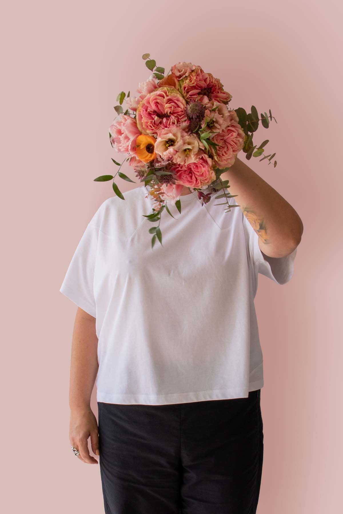 Asmuss Panelled T-shirt in White Organic Cotton and Recycled Polyester worn by Clare with a beautiful bunch of flowers in front of her face.