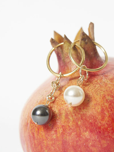 Mismatched earrings hanging on the top of a pomegranate cropped